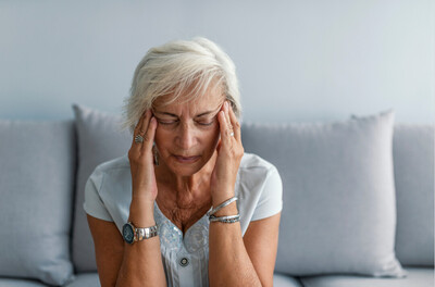 older woman holding both temples in discomfort before chiropractor appointment for headache relief