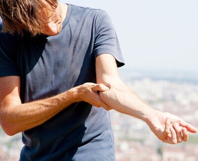 man rubbing his elbow in pain