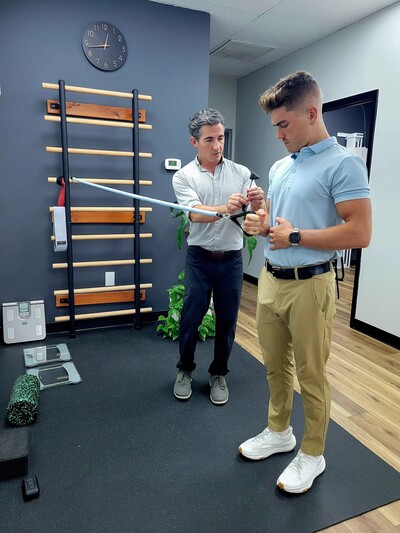athletic man getting shoulder rehab exercises from a sports chiropractor 
